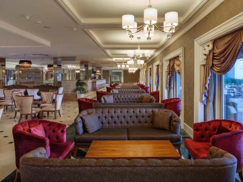 Elegant hotel lobby with comfortable sofas, armchairs, and large windows with drapes.