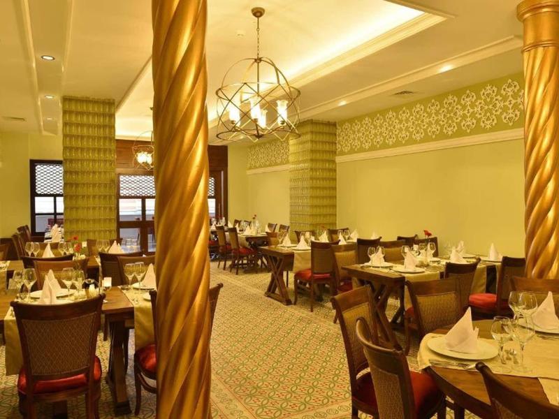 Elegant restaurant with soft lighting, gold-colored pillars, and set dining tables.