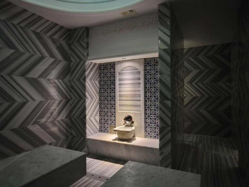 Dark room with geometric patterns and a small statue on a lit platform.