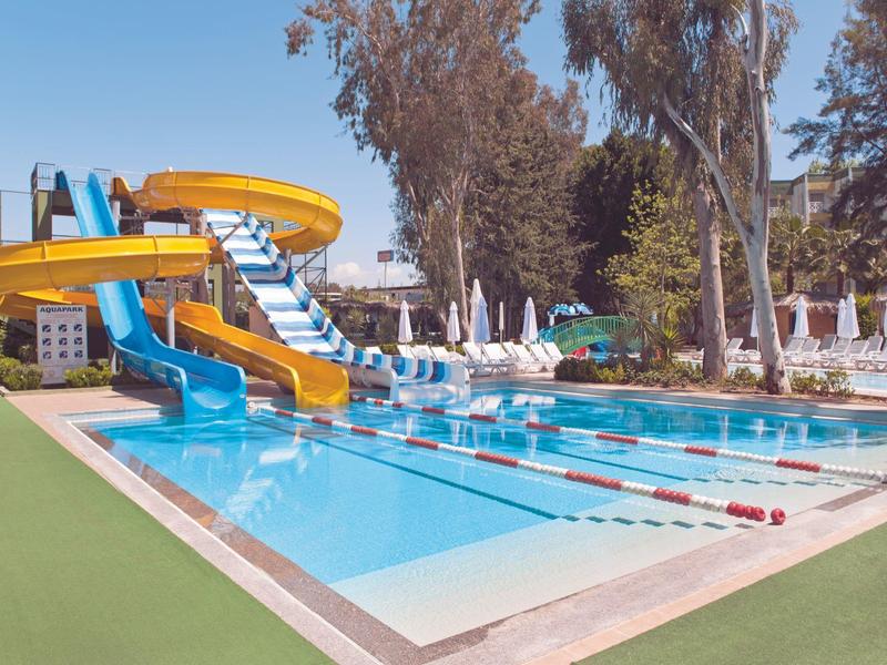 Rekreační bazén s vodními skluzavkami, plaveckými dráhami a lehátky na slunném místě