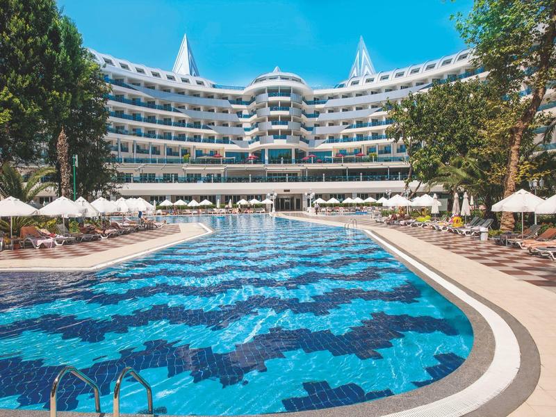 Moderní hotelový komplex s velkým venkovním bazénem a lehátky pod slunečníky.