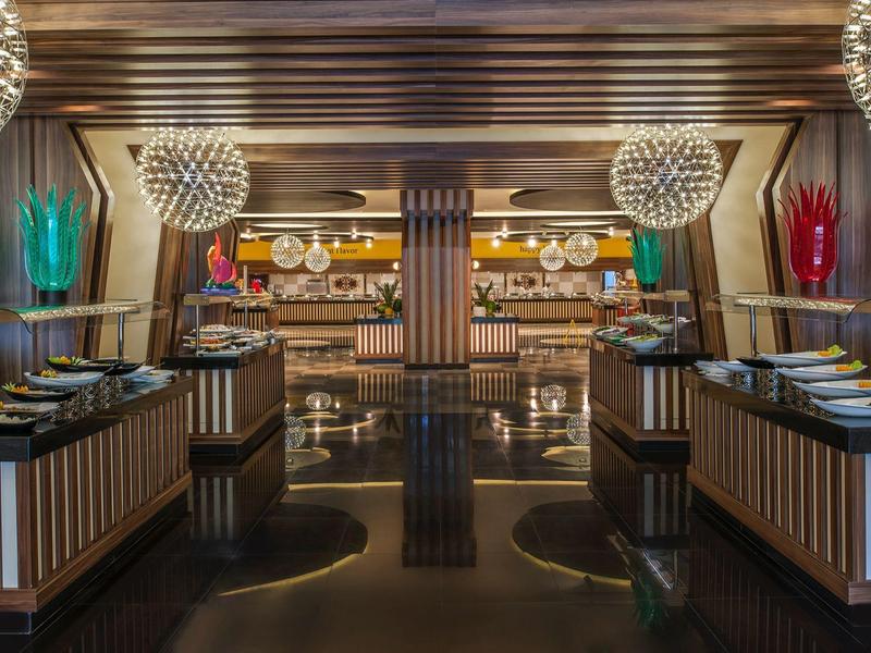 Elegantní hotelová restaurace s tmavou podlahou, dřevěným stropem a moderním osvětlením.