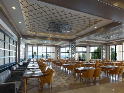 Salle à manger d'hôtel moderne avec de nombreuses tables, chaises jaunes et grandes fenêtres.