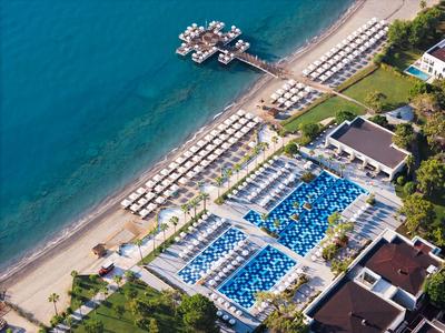 Vue aérienne d'un hôtel avec deux grandes piscines et des parasols sur la plage.