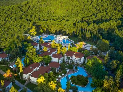 Grand complexe hôtelier avec plusieurs piscines entouré d'une forêt dense verte.