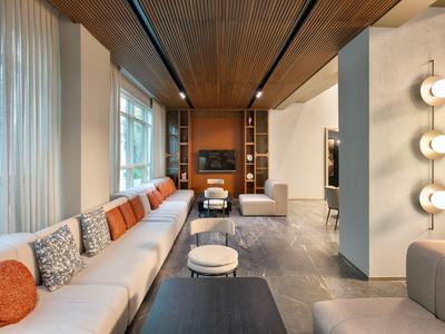 Chambre d'hôtel moderne avec grand canapé, plafond en bois, grandes fenêtres et éclairage élégant.