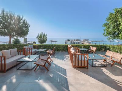 Terrasse ouverte avec mobilier moderne et vue sur la mer sous un ciel clair.