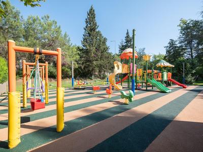Aire de jeux colorée avec balançoires, toboggans et structures d'escalade dans un parc ensoleillé.