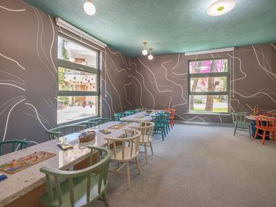 Salle de petit déjeuner lumineuse avec chaises colorées et longues rangées de tables dans l'hôtel.