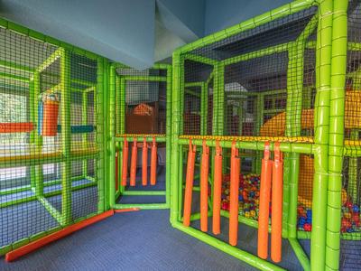 Aire de jeux intérieure colorée avec des structures rembourrées vertes et orange dans un hôtel.