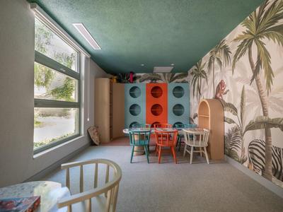 Coin repas douillet avec armoire colorée et grandes fenêtres dans une chambre d'hôtel.