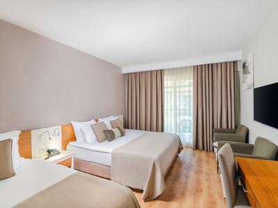Chambre d'hôtel moderne avec deux lits, rideaux et sol en bois.