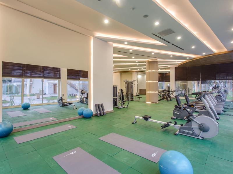 Salle de sport moderne avec tapis de yoga, ballons et vélos d'appartement.