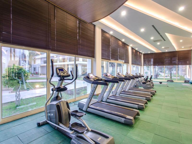 Salle de sport moderne avec tapis roulants et équipement près de grandes fenêtres.