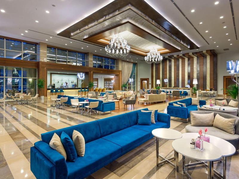 Grand salon d'hôtel moderne avec canapés bleus et tables blanches élégantes.