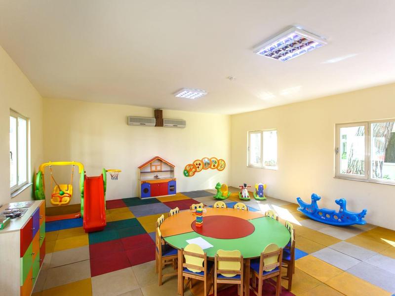 Salle de jeux colorée avec tapis, table ronde et jouets pour enfants.
