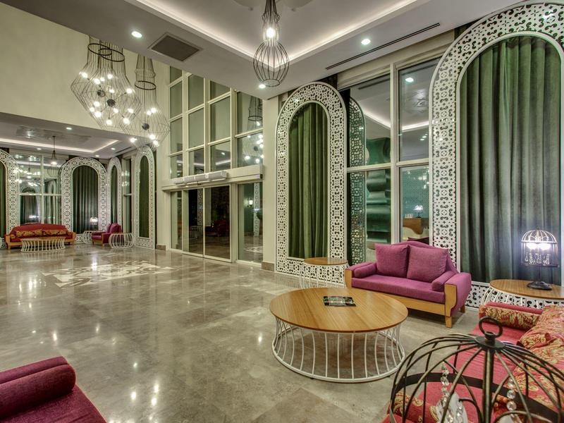 Lobby d'hôtel élégant avec canapés colorés et grandes fenêtres ornées.