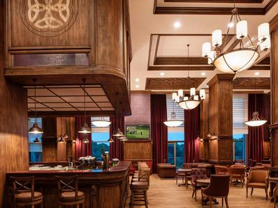 Gezellige houten bar en eetruimte met warme verlichting en elegante kroonluchters in een hotel lounge.