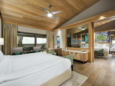 Modern hotel room with double bed, wooden accents, and sea view.