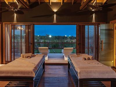 Gezellige spakamer met massagetafels en uitzicht op buitenzwembad en stadslichten bij schemer.