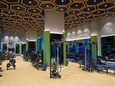 Moderner Fitnessraum in einem Hotel mit verschiedenen Trainingsgeräten und einem detaillierten Deckendesign.