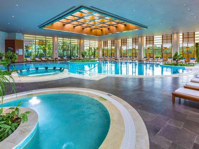Moderner Indoor-Poolbereich mit Jacuzzi, großen Fenstern und Liegestühlen in einem Hotel.