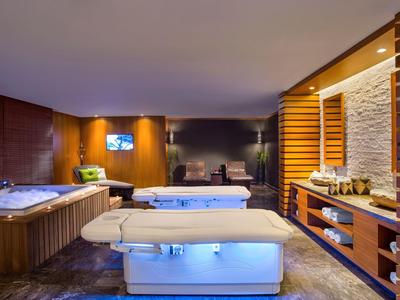 Modern eingerichteter Wellnessraum mit Massageliegen, Whirlpool und warmem Holzambiente.