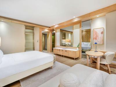 Modernes Hotelzimmer mit großem Bett, Holzmöbeln und sanfter Beleuchtung.