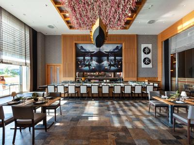 Modernes Restaurant mit großen Fenstern, Holzvertäfelung und eleganter Beleuchtung.