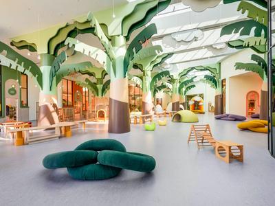 Helle Hotellobby mit grünen Baumstützen und modernen Sitzmöbeln in freier Anordnung.