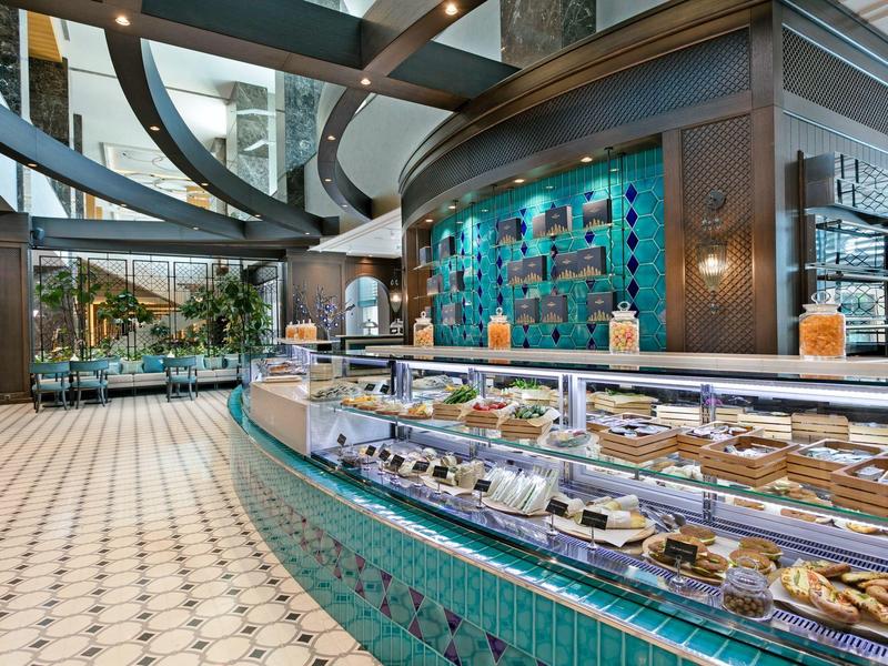 Moderne bakkerijtoonbank met diverse gebakjes in een ruime, goed verlichte café-inrichting.