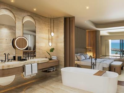 Modern hotel room with open bathroom and freestanding bathtub overlooking the sea.