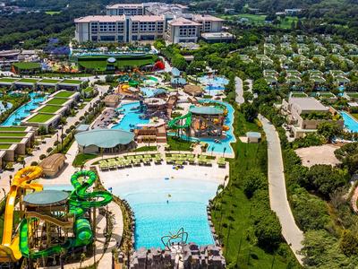Grande resort con più piscine, aree verdi e scivoli d'acqua in un ambiente tropicale.