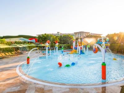 Piscina per bambini con giochi d'acqua e scivoli colorati al tramonto.