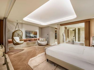 Ampia camera d'hotel con letto grande, posti a sedere moderni e toni caldi.