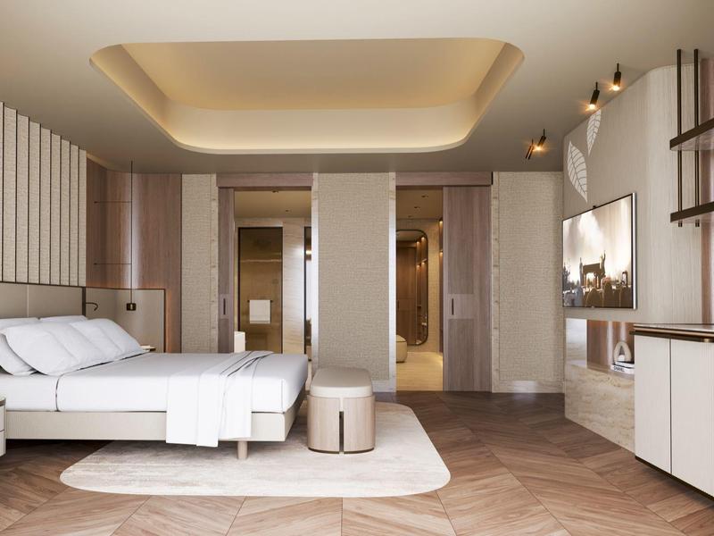 Modern hotel room with double bed, rug, ottoman, and stylish lighting.