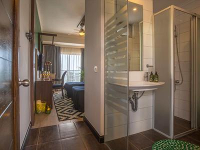 Camera d'hotel moderna con bagno aperto e doccia, vista sulla camera da letto.