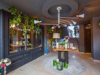 Moderner, dunkler Raum mit runden Deckenlampen, Holzregalen, grünen Pflanzen und Blumenarrangements.