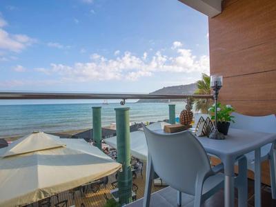 Balcone con tavolo, sedie e vista sul mare sotto un cielo limpido