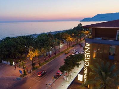 Blick auf Küstenstraße mit Bäumen, Autos und Hotelgebäude bei Dämmerung.