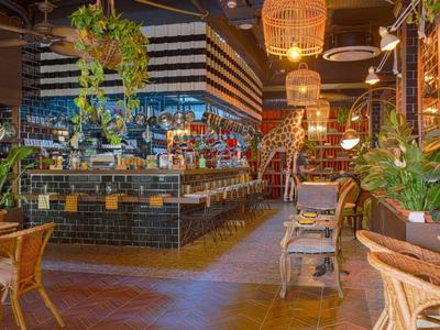 Gemütliche Bar mit Holzmöbeln, Hängepflanzen und warmem, gedämpftem Licht.