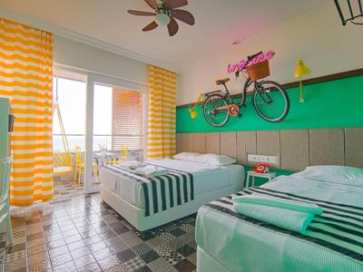 Habitación de hotel luminosa con dos camas individuales y balcón con vistas al mar.