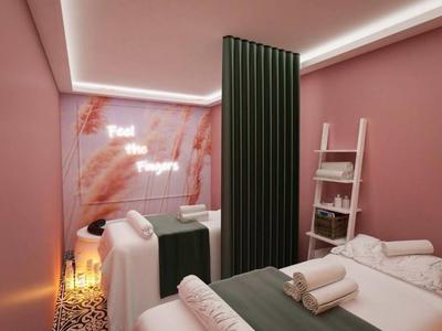 Zwei Behandlungsbetten in einem rosa Raum mit grünen Vorhängen und sanfter Beleuchtung.