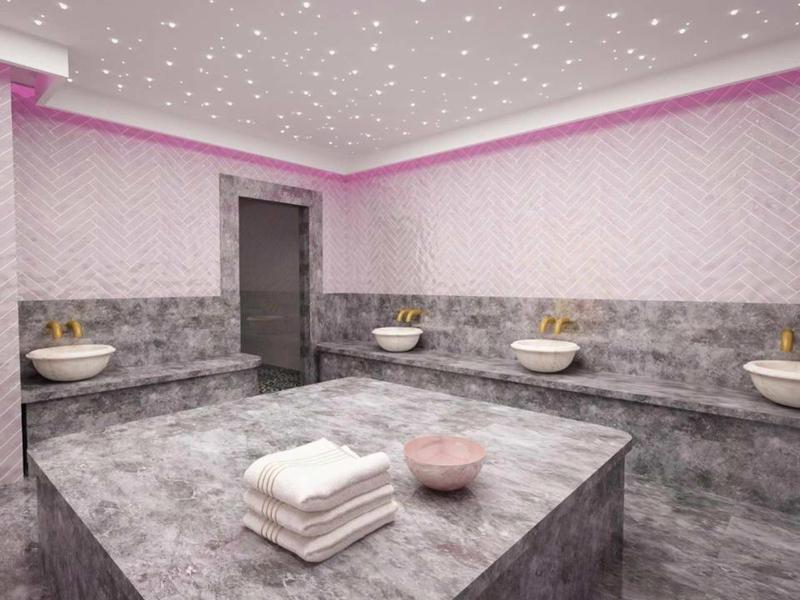 Moderner Hammam mit grauen Marmorflächen, Waschbecken und Sternenhimmel-Decke in warmem Licht.