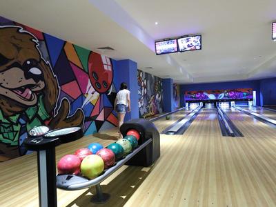 Binnenzicht van een bowlingbaan met kleurrijke muren en meerdere bowlingballen.