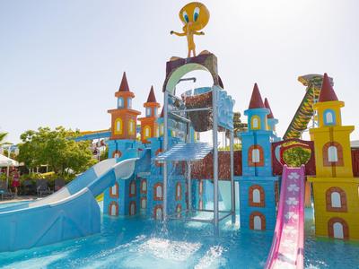 Kolorowy park wodny z zjeżdżalniami i dużą wodną figurą w kształcie tukana.