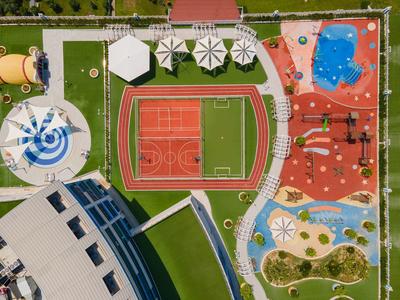 Widok z lotu ptaka na centrum rekreacyjne z boiskiem sportowym, basenami i strefami wypoczynkowymi.