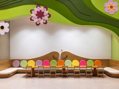 Kolorowy nowoczesny pokój dziecięcy z drewnianymi stołami, krzesłami i poduszkami w wesołych kolorach.