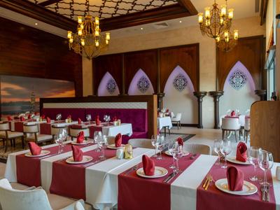 Elegancka restauracja z czerwono-białymi nakryciami stołów i żyrandolami na suficie.