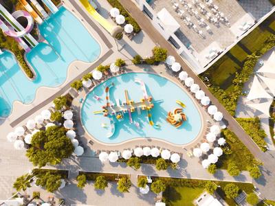 Widok z lotu ptaka na plac zabaw wodny z zjeżdżalniami i parasolami w ośrodku hotelowym.